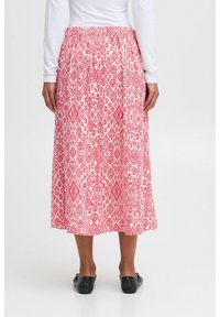 Jupe évasée, longueur cheville, en rose clair avec des motifs géométriques et floraux blancs. Taille élastique et texture de tissu fluide.