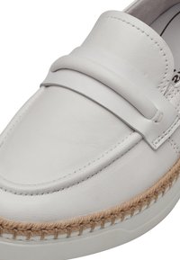 Mocassin en cuir blanc avec un détail en jute tressé le long de la semelle, présentant un design cousu et une texture lisse. Style minimaliste.