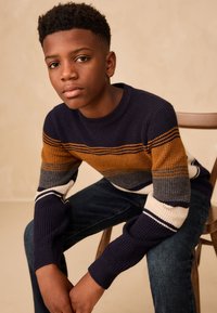 Pull en maille avec rayures horizontales bleu marine, orange, gris et blanc. Encolure ronde et poignets côtelés avec une finition texturée.