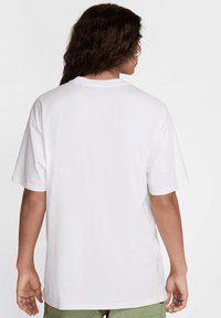 Camiseta de algodón blanca con mangas cortas y corte recto. Presenta un cuello redondo clásico y sin logos o patrones visibles.