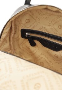 Svart läderryggsäck med interiör i beige tyg som har upprepande texten "CAFE NOIR". Inkluderar en dragkedjeficka och slät foder.