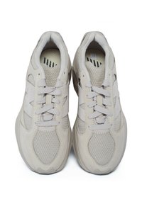 Sneakers atletici di colore beige chiaro, caratterizzati da una tomaia in rete, dettagli in suede testurizzato, sei occhielli per i lacci e una suola imbottita, progettati per il massimo comfort.