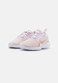 Zapatillas deportivas de malla rosa claro con suelas blancas, que presentan un swoosh de Nike en oro rosa y cordones en rosa pálido; diseñadas para comodidad y soporte.