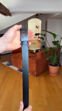 Musta nahkavyö, jossa on suorakaiteen muotoinen solki ja siihen leikattu "CK"-logo. Vyö on sileäpintainen, matta viimeistelyllä ja sen kokoa voi säätää.