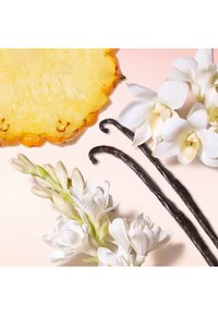 Tranche d'ananas, fleurs d'orchidée blanche et deux gousses de vanille foncées sur un fond rose doux. Textures lisses, tons jaunes vifs et blancs.