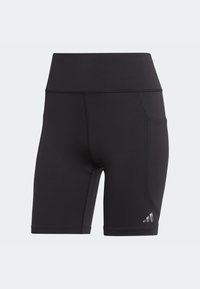 Pantalones cortos deportivos negros hechos de tejido elástico, con una cintura alta, bolsillo lateral y logo reflectante cerca del dobladillo. Textura suave.