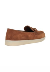 Brown suede slip-on shoe with a rounded toe, featuring a front flap and gold hardware accents, and a light-colored sole.