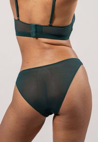 Donkergroen gaas bh en slipje set met verstelbare bandjes en geschulpte randen, die een zachte textuur en minimalistisch ontwerp benadrukt.