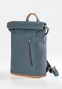 Rolltop-Rucksack aus dunkelgrünem Leder mit einem Boden aus hellbraunem Leder. Verfügt über eine vordere Reißverschlusstasche und verstellbare Träger. Glatte Oberfläche.