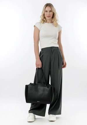 Zwarte leren handtas met een gestructureerd ontwerp en een gladde textuur, voorzien van dubbele handvatten en een ritssluiting. Gecombineerd met grijze broek en een witte top.