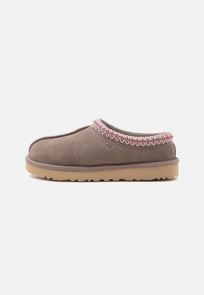 Chausson marron en daim à enfiler avec garniture cousue rose et blanche et semelle en caoutchouc couleur fauve, vu de profil sur fond blanc.