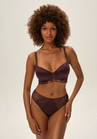 Ciemnoczerwony zestaw bielizny składający się z biustonosza z koronkowym wykończeniem, z regulowanymi ramiączkami oraz dopasowanych majtek z wysokim stanem z koronkowymi akcentami.