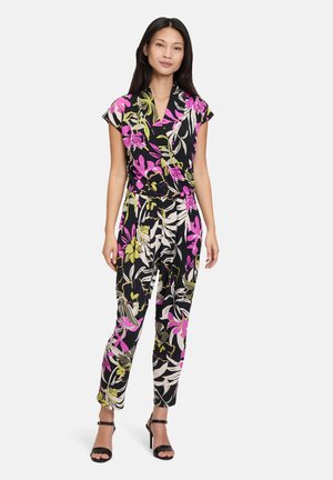 Completo floreale nero con motivi vivaci in rosa, bianco e oliva. Maniche corte, vita cinchata e gambe affusolate, abbinato a tacchi open-toe.