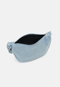 Světle modrá denimová crossbody taška s otevřeným zipem, stříbrnou sponou na nastavitelné šňůře a bílým vyšitým logem Levi's na přední straně.