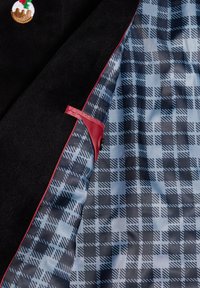 Svart kappa med blå och svart rutig foder, röd kant längs kanten och en broderad julpudding-pin på reversen.