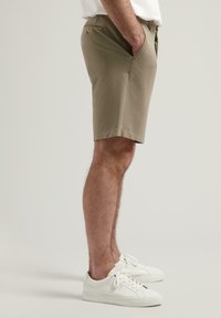 Șorturi din bumbac kaki, cu buzunare laterale, design tailored și croială dreaptă. Asortate cu adidași albi.
