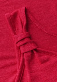 Top de tela roja con detalle anudado en el hombro, textura suave y escote redondeado, con un color vibrante y uniforme en toda la prenda.