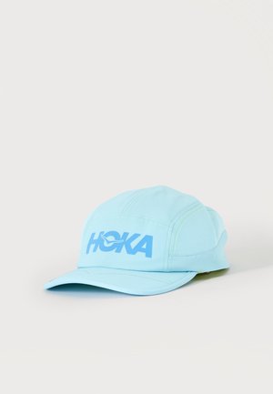 Casquette de sport bleu clair avec visière incurvée et panneaux latéraux en mesh, avec un grand logo "HOKA" à l'avant.
