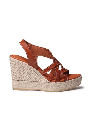 Hnedý kožený klinový sandál s prekríženými remienkami, základňou obalenou jutou a textúrovaným povrchom. Má biele prešitie pozdĺž okrajov.