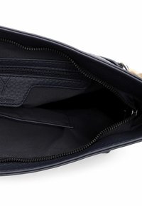 Granatowa skórzana torba wnętrze z zamykaną na suwak kieszenią, gładką podszewką i przeszytym wykończeniem głównej komory.