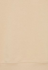 Tessuto di felpa beige chiaro con una consistenza morbida e liscia. Presenta un orlo e polsini a costine, evidenziando un design semplice e pulito.