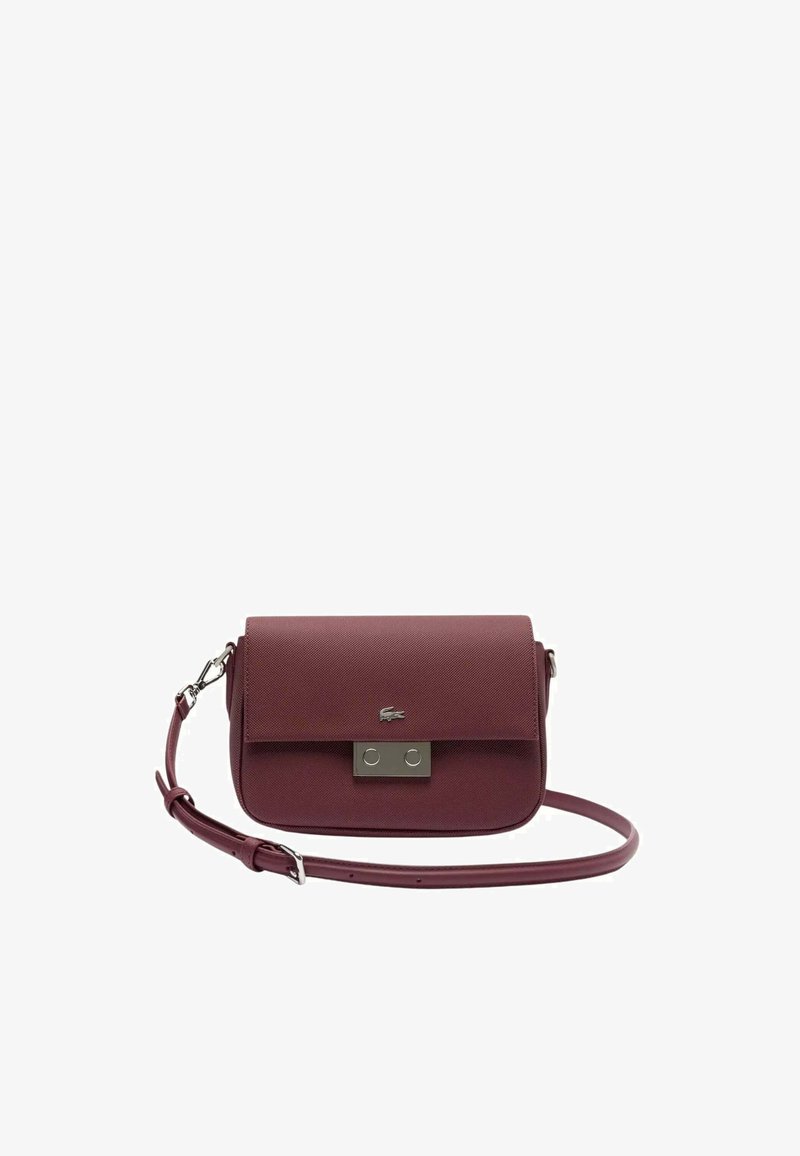 Sac à main structuré de couleur marron foncé avec une texture lisse, une fermeture à boucle en métal argenté et une sangle ajustable. Présente un logo embossé à l'avant.