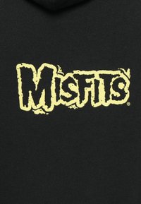 Black hoodie featuring the word "Misfits" in large, textured yellow lettering, displayed prominently on the front.