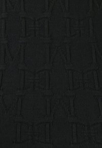 Černá látka s vyvýšeným opakujícím se vzorem, který obsahuje písmena a tvary. Textura je hladká s jemným leskem.