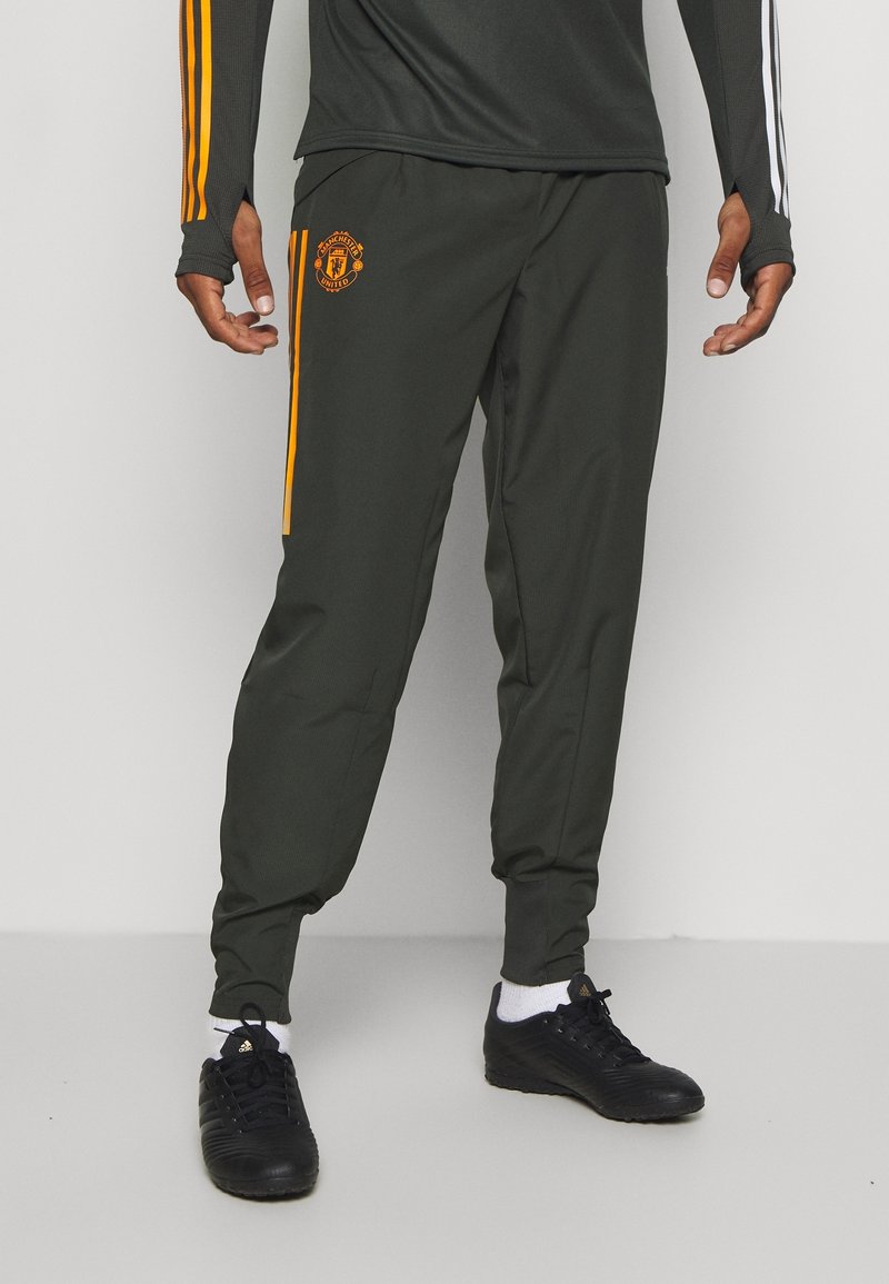 Grüne Sporthose aus glattem Stoff mit seitlichen orangen Streifen, einem Logopatch und schmalen Fußbündchen.