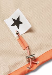 Tissu beige avec un motif en grille, accent orange et une étiquette en forme d'étoile noire. Comprend un fermoir en métal argenté et des détails en cordon.