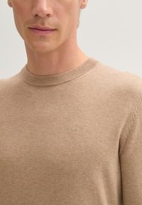 Beige, lichtgewicht trui met een ronde hals. Beschikt over een fijne brei-textuur en een subtiele logo in het bovenste linker gebied. Minimalistisch ontwerp.