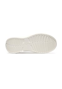 Suela de zapato blanca texturizada con ranuras curvas y un logo central en relieve en el caucho, vista desde la parte inferior.
