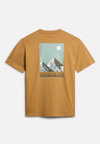 Camiseta de algodón marrón con cuello redondo, que presenta un gráfico de montaña en azul y blanco en la parte trasera, y el texto "NAPAPIJRI geographic" debajo.