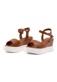 Bruine leren wedge sandaaltjes met een open teen, verstelbare enkelbandjes en een chunky witte platformzool met branding.