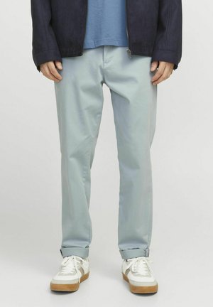 Pantalones en azul claro hechos de una tela suave, con un corte relajado, dobladillos enrollados, y combinados con zapatillas blancas y una chaqueta azul marino.