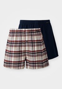 Un par de calzoncillos: uno presenta un estampado de cuadros en beige, rojo y azul marino; el otro es de un solo color azul marino. Ambos tienen cinturillas elásticas.