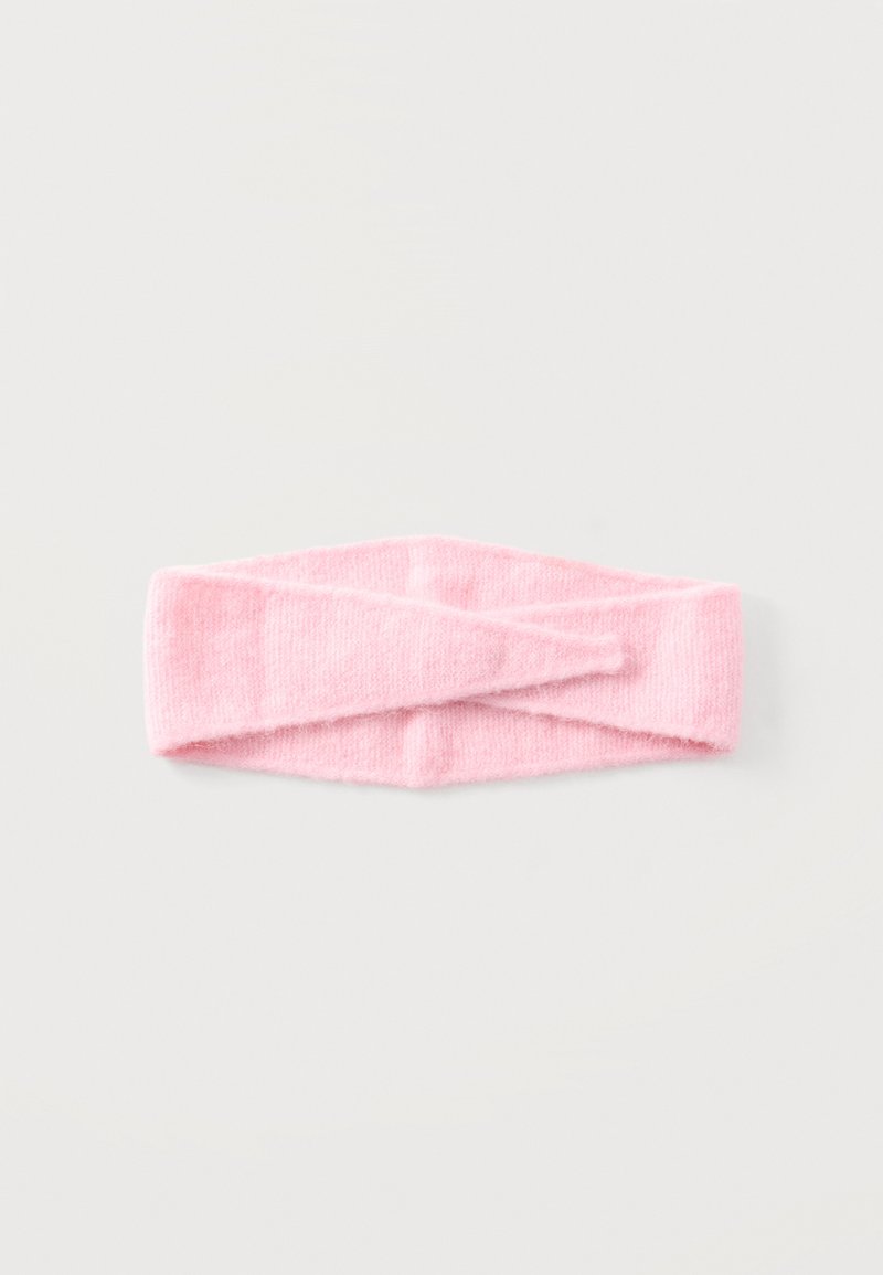 Bandeau tricoté rose doux avec un design de nœud torsadé, posé à plat sur une surface claire.