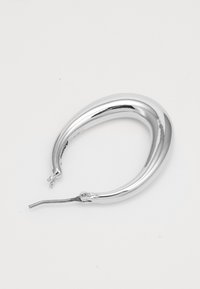 Boucle d'oreille en forme de croissant poli argenté avec une fine tige et un fermoir sur fond blanc.