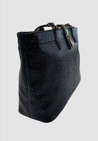 Borsa a tracolla in pelle nera con texture, dotata di manici corti e un charm a forma di lucchetto dorato, inclinata su uno sfondo grigio chiaro.