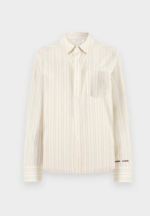 Πουκάμισο χρώματος κρέμα με κατακόρυφες ρίγες, μακριά μανίκια, τσέπη στο στήθος και κεντημένο όνομα της επωνυμίας σε αντίθεση στη μανσέτα.