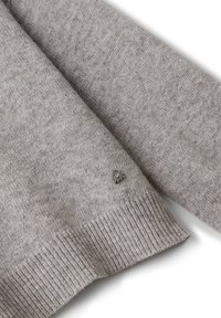 Szary sweter dzianinowy z ribbowanymi mankietami, prezentujący mały detal logo na dolnym brzegu. Miękka tekstura i swobodny fason.