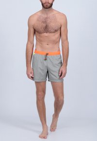 Shorts de bain pour hommes en tissu avec un motif géométrique noir et blanc, dotés d'un cordon de serrage orange et de deux poches latérales.