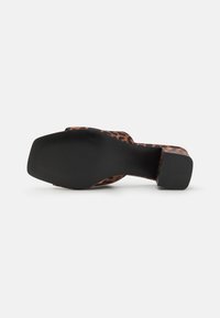 Svarte hæler sandaler med leopardmønster på overdelen, teksturert såle, og solid svart hæl. Formen er åpen tå med bred stroppedesign.