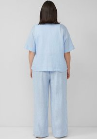 Lichtblauw linnen overhemd met korte mouwen, gecombineerd met lichtblauwe en witte gestreepte wijde broek. Eenvoudig ontwerp, zachte textuur, relaxte pasvorm.