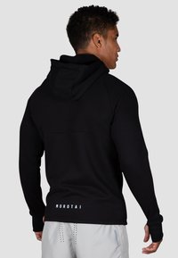 Schwarzer Hoodie mit schmaler Passform, strukturiertem Stoff und einem Logo am hinteren Saum. Verfügt über eine geräumige Kapuze und gerippte Bündchen für zusätzlichen Komfort.