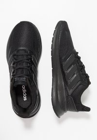 Czarne buty sportowe z siateczkową cholewką, teksturowanymi powierzchniami, amortyzowaną podeszwą oraz trzema czarnymi paskami po bokach, wyposażone w sznurowadła i wyściełany kołnierz.