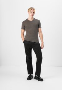 Gray short-sleeve t-shirt paired with black corduroy pants, complemented by black shoes with a textured finish and distinct sole design.