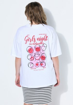 Osoba nosząca białą, oversize'ową koszulkę z różowym i czerwonym napisem „Girls night on midsummer” oraz ilustracjami kieliszka wina na plecach.