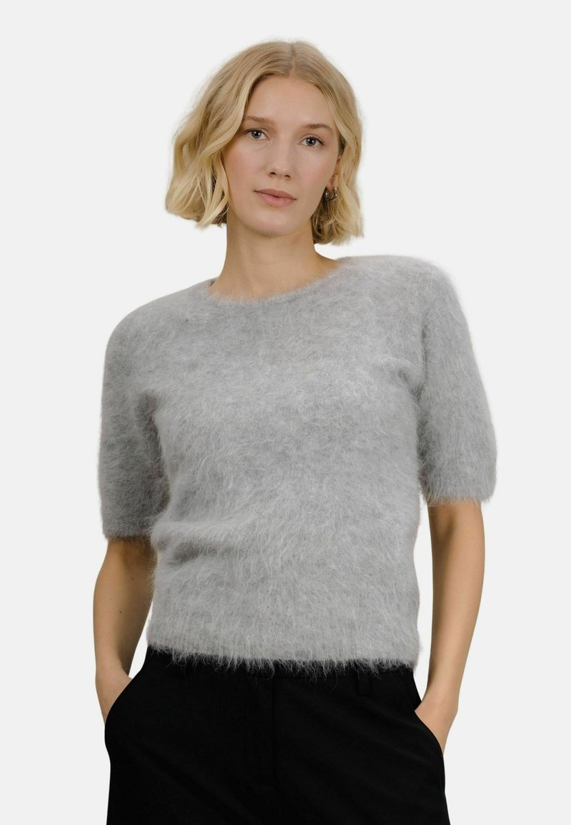 Lysegrå kortermet genser laget av luftig, mykt materiale med rund hals og avslappet passform. Brukt sammen med mørke bukser.