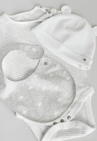 Grauer und weiß gestreifter Strampler mit Druckknöpfen, ein grauer Latz mit weißen Sternen und eine einfarbige weiße Mütze mit runden Ohren.